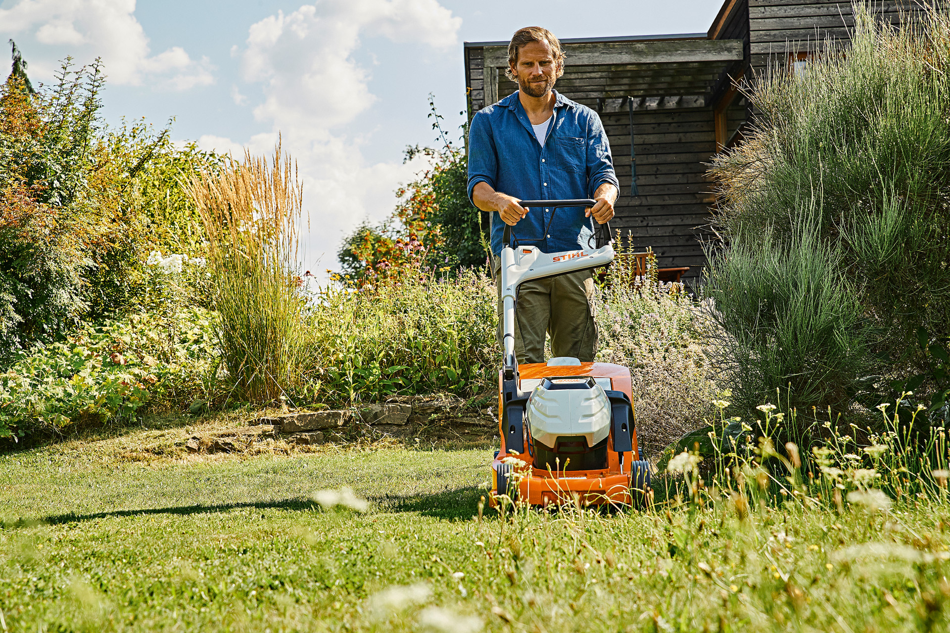 Čovek koristi STIHL baterijsku kosačicu RMA 448 P-C za održavanje travnjaka na zaraslom imanju leti